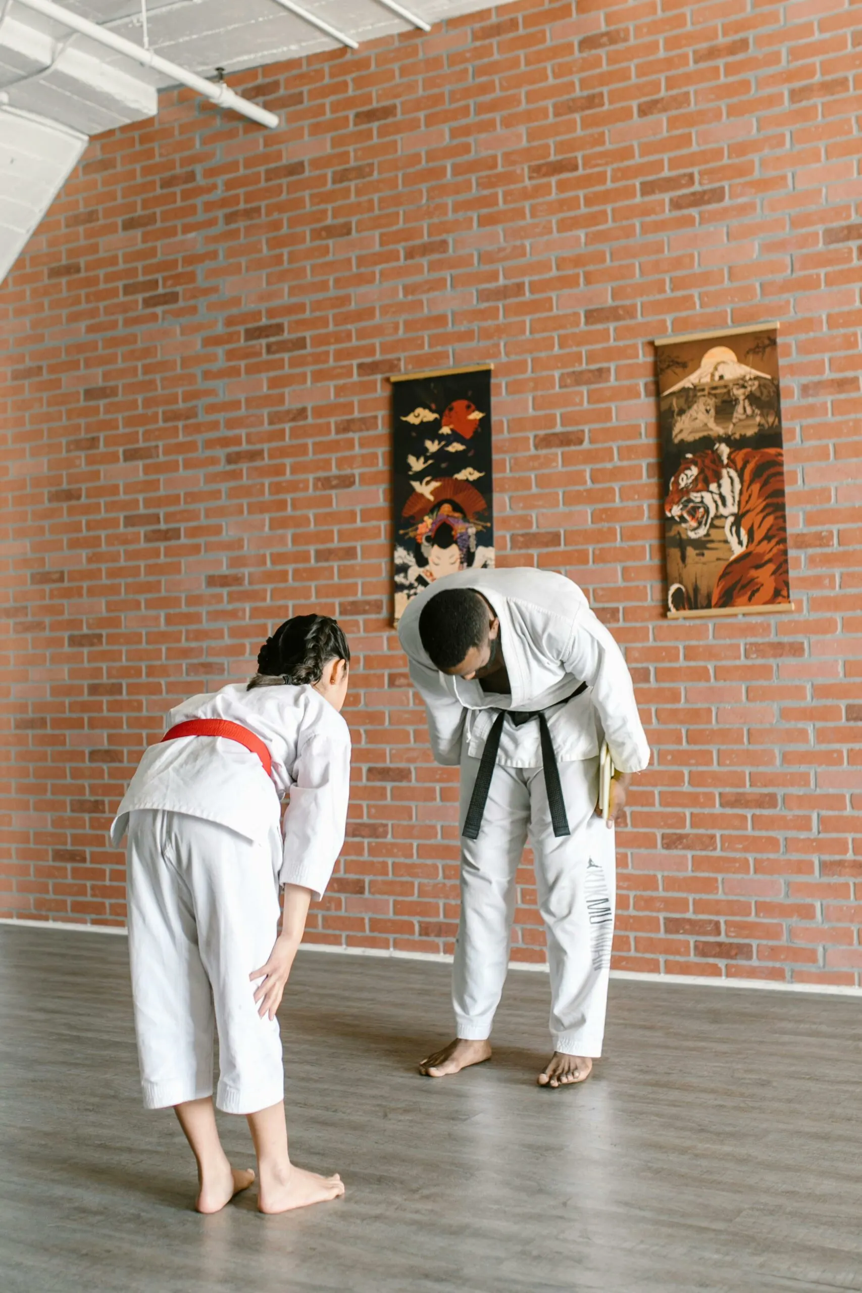 Due judoka in judogi bianco, uno più piccolo e uno con la cintura nera, si salutano con un inchino sul tatami